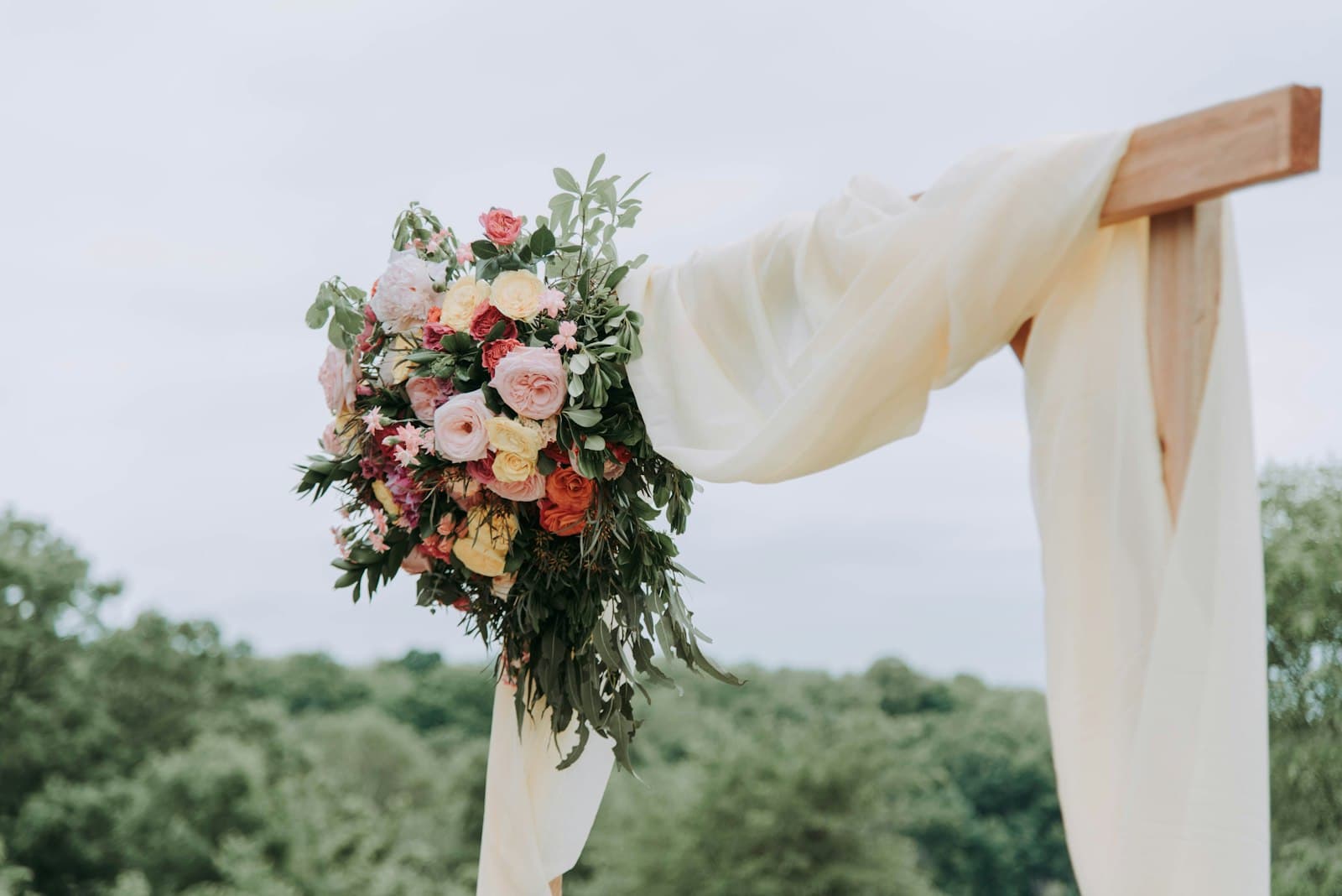 Bouquet of pink and white flowers tied to the corner of a draped wedding arch