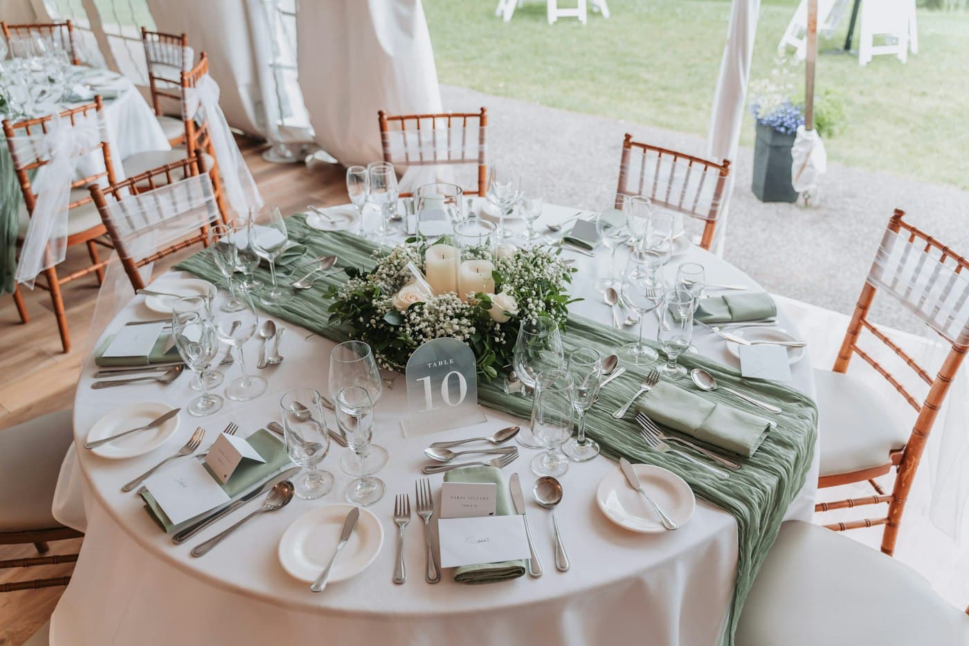 Round reception table set with place cards and a greenery centerpiece